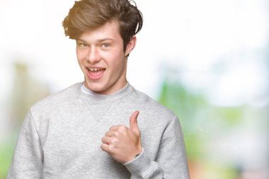 Hareketi el ile mutlu yaşasın yapıyor izole arka plan üzerinde sweatshirt giyen genç yakışıklı sportif adam. Başarı gösteren kameraya bakarak ifade onaylama.