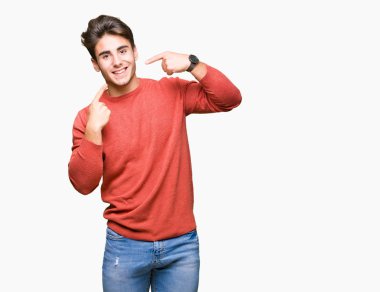 Tecrit edilmiş, güler yüzlü, kendine güvenen, parmaklarını, dişlerini ve ağzını gösteren genç yakışıklı bir adam. Sağlık kavramı.