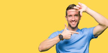 Yakışıklı Doktor adam elleriyle yapım çerçeve ve parmakları ile mutlu yüz gülümseyen izole arka plan üzerinde tıbbi üniforma. Yaratıcılık ve Fotoğrafçılık kavramı.