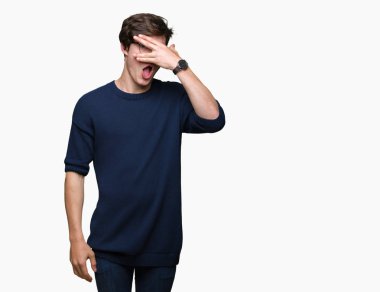 Mahcup ifadeyle parmaklarımın arasından seyir yüz ve gözler el ile kapsayan şok bakmak izole arka plan üzerinde gözlük takan genç yakışıklı adam.