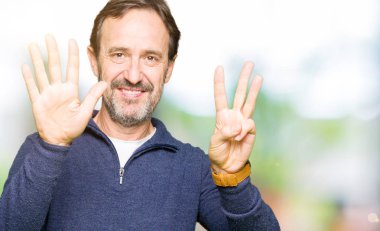 Bir kazak gösteren ve parmakları ile işaret giyen orta yaş yakışıklı adam kendinden emin ve mutlu gülümseyerek süre sekiz numara.