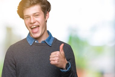 Genç yakışıklı zarif adam izole arka plan hareketi el ile mutlu Yaşasın yapıyor. Başarı gösteren kameraya bakarak ifade onaylama.