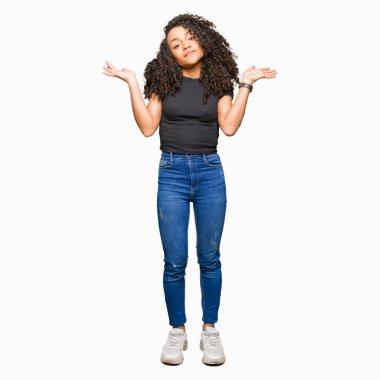 Kıvırcık saç clueless ve kollar ve elleri ile karıştı ifade ile genç güzel kadın kaldırdı. Şüphe kavramı.