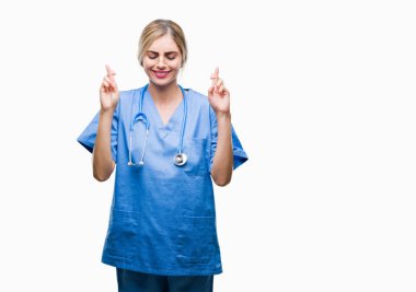 Genç güzel sarışın doktor cerrah hemşire kadın geçiş parmakları umut ve gözleri kapalı ile gülümseyen izole arka plan yüzünden. Şans ve batıl kavramı.