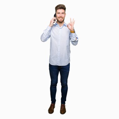 Genç yakışıklı adam iş parmak, mükemmel sembolü ile ok işareti yapıyor Smartphone cep telefonu ile konuşmak