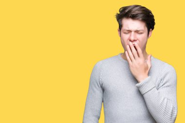 Yakışıklı delikanlı izole arka plan üzerinde kış kazak giyen el ağzıyla kapsayan yorgun esneme sıkılmış. Restless ve uyku hali.