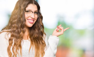 Kameraya bakarak yan el ve parmak ile işaret gözlüklü kocaman bir gülümseme ile yüzünde, genç güzel kadın.