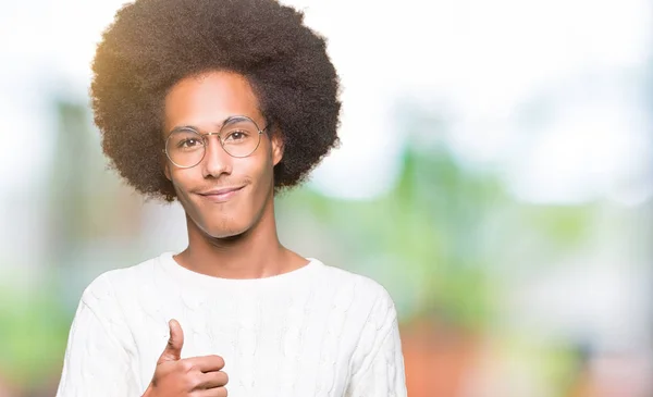 Young african american man with afro hair wearing glasses doing happy thumbs up gesture with hand. Approving expression looking at the camera showing success.