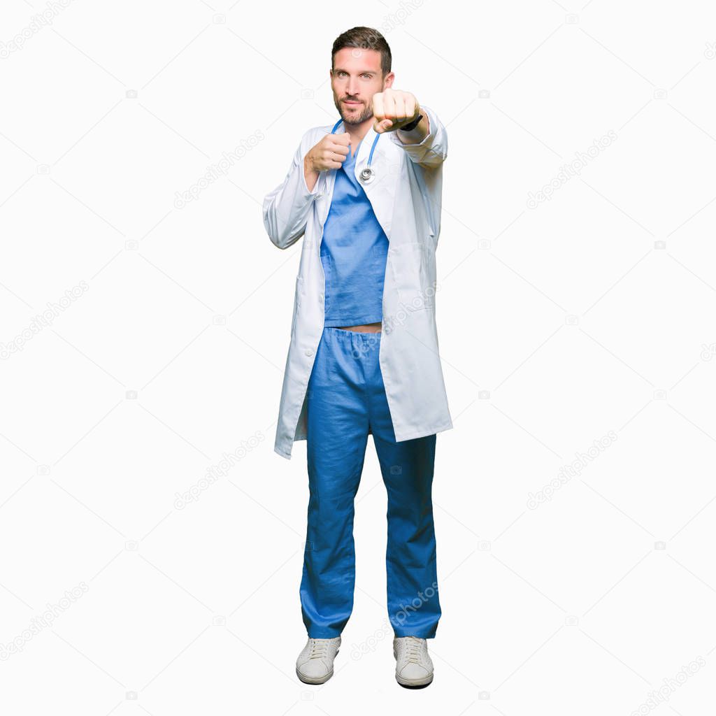 Handsome doctor man wearing medical uniform over isolated background Punching fist to fight, aggressive and angry attack, threat and violence