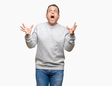 Üzerinde spor kazak giyen orta yaş Arap adam deli kutluyor arka plan izole ve başarı için kaldırdı kollarını açarak hayrete ve heyecanlı çığlık gözleri açık. Kazanan kavramı