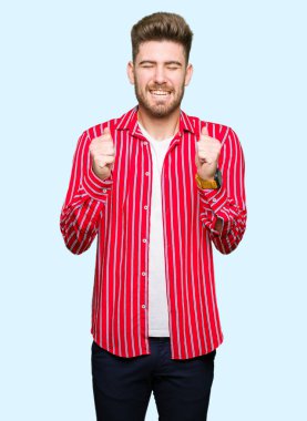 Yakışıklı delikanlı giyen kırmızı gömlek kolları olan başarı için heyecanlı zafer kutluyor gülümseyen kaldırdı. Kazanan kavramı.