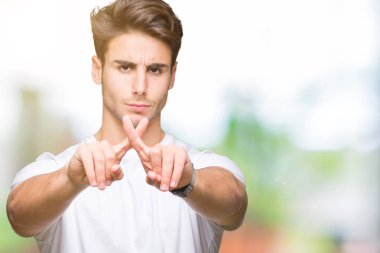 Eksi işareti yapıyor izole arka plan ret ifade geçiş parmakları üzerinde beyaz t-shirt giyen genç yakışıklı adam