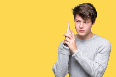 El hareketi ile sembolik silah tutan, çekim silah, kızgın yüz öldürmek oynamaya izole arka plan üzerinde kış kazak giyen genç yakışıklı adam