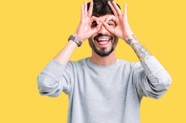 Dilini, parmaklarının arasından baktığını yapışmasını dürbün gibi ok jest yapıyor izole arka plan üzerinde sweatshirt giyen genç yakışıklı adam. Deli ifade.