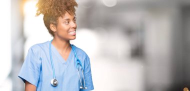 İzole arka plan uzak tarafına gülümseme ile yüzünde, doğal ifade seyir üzerinde genç Afro-Amerikan doktor kadın. Kendine güvenen gülüyor.