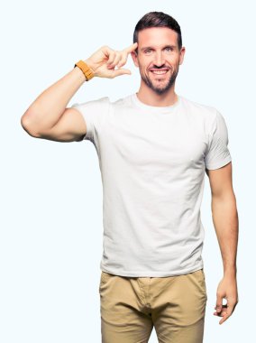 Casual beyaz t-shirt gülen bir parmak, harika bir fikir ya da düşünce, iyi hafıza ile baş gösteren giyen yakışıklı adam