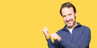 Orta yaş yakışıklı adam bir kazak giyen el ve başparmak yukarı arka işaret, kendinden emin gülümseyerek