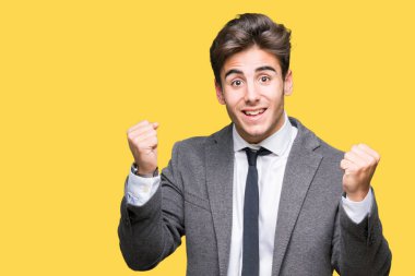 Giyen genç iş adamı takım elbise ve kravat izole arka plan ile silah kaldırdı sürpriz ve başarı için hayran kutluyor ve açık gözler üzerinde. Kazanan kavramı.