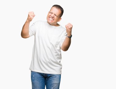 Orta yaş Arap adam wearig beyaz t-shirt üzerine arka plan çok mutlu ve heyecanlı kaldırdı, silah ile kazanan jest yapıyor gülümseyen ve başarı için çığlık izole. Kutlama kavramı.