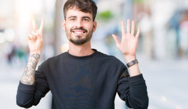 Yakışıklı delikanlı gösterilen ve parmakları ile işaret izole arka plan üzerinde kendinden emin ve mutlu gülümseyerek süre yedi numara.