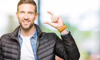 Yakışıklı adam giyen kış ceket gülümseyen ve boyutu işi el ile kendinden emin eller parmakları ile seyir ve fotoğraf makinesi oturum açın. Ölçü kavramı.