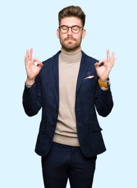 Genç yakışıklı iş adam gözlük rahatla ve gülümseyen gözlerle kapalı parmak jestle meditasyon yapıyor. Yoga kavramı.