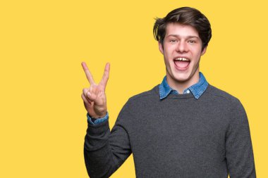 Mutlu yüz zafer işareti yaparken kameraya göz kırpıyor ile gülümseyen izole arka plan üzerinde genç yakışıklı zarif adam. İki numaralı.