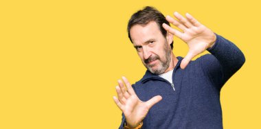 Orta yaş yakışıklı adam bir kazak giyen Gülümseyerek kare avuç içi ve parmaklar kullanarak, kamera perspektifi kullanarak