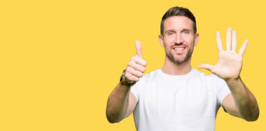 Yakışıklı adam gösterilen ve parmakları ile işaret casual beyaz t-shirt giyen süre kendinden emin ve mutlu gülümseyerek 6 numara.