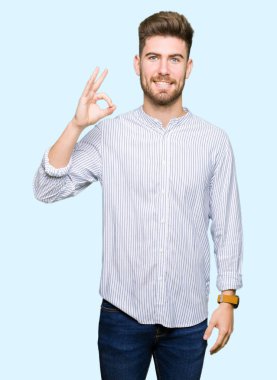 El ve parmak ile ok işareti yapıyor olumlu gülümseyen yakışıklı delikanlı. Başarılı ifade.