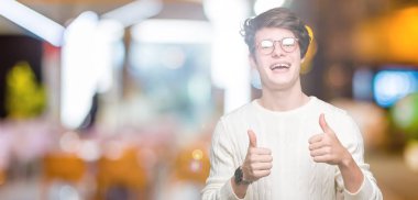 Yakışıklı delikanlı izole arka plan başarı işareti el ile pozitif jest yapıyor üzerinde gözlük takan başparmak gülümseyen ve mutlu. Neşeli bir ifadeyle, kazanan jest kameraya bakıyor.