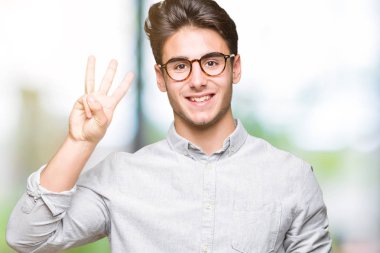 Gösterilen arka plan üzerinde gözlük takan genç yakışıklı adam izole ve parmakları ile işaret üçüncü gülümseyen ise kendinden emin ve mutlu.