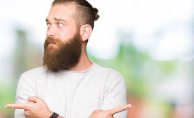 Casual kazak giyen genç sarışın adam her iki parmak ile işaret eden, farklı yönde katılmıyorum