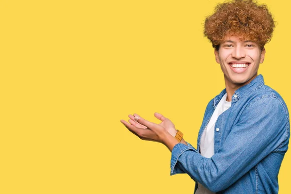 年轻英俊的男子与非洲头发牛仔夹克指着一边用手和张开的手掌 呈现广告微笑快乐和自信 — 图库照片