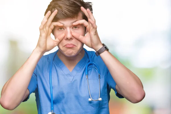 年轻的医生穿着医疗制服在孤立的背景下试图用手指睁开眼睛 昏昏欲睡 早晨疲劳 — 图库照片