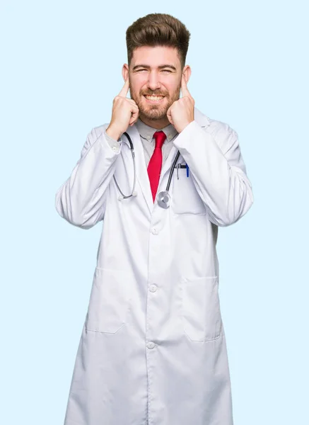 Молодий Красивий Лікар Чоловік Медичному Пальто Покриває Вуха Пальцями Роздратованим — стокове фото