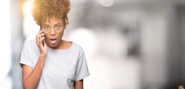 Genç Afro-Amerikan kadın Smartphone'da izole arka plan üzerinde bir sürpriz yüz, korkuyor ve heyecanlı korku ifadesi ile şok korkmuş söz