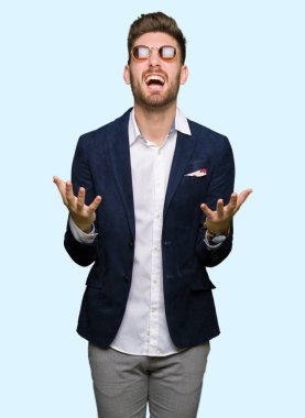 Güneş gözlüğü ve moda ceket çılgın ve kızgın bağırarak ve agresif ifade ve silah kaldırdı bağırmaya giyen genç yakışıklı zarif adam. Hayal kırıklığı kavramı.