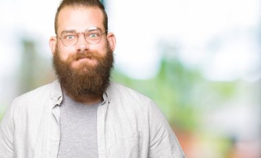 Gözlük giyen genç sarışın adam komik yüzü yanakları kabarık. Ağız hava ile şişirilmiş, çılgın ifade.