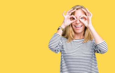 Giyen güzel genç kadın kazak dilini, parmaklarının arasından baktığını yapışmasını dürbün gibi ok jest yapıyor izole arka plan üzerinde çizgili. Deli ifade.