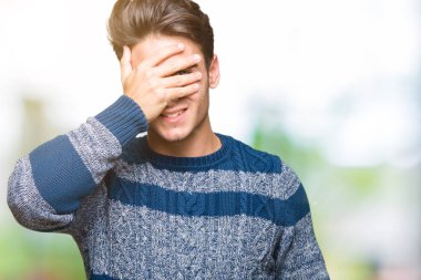 Yakışıklı genç gülümseyen ve gözler için sürpriz kapsayan yüz el ile gülüyor izole arka plan üzerinde. Kör kavramı.