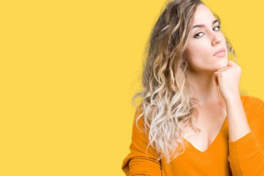 Güzel sarışın genç kadın elle çene düşünme hakkında soru, dalgın ifade izole arka plan üzerinde. Düşünceli yüzüyle gülümsüyor. Şüphe kavramı.