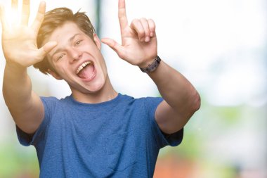 Üzerinde gösterilen ve parmakları ile işaret izole arka plan mavi t-shirt giyen genç yakışıklı adam kendinden emin ve mutlu gülümseyerek süre yedi numara.