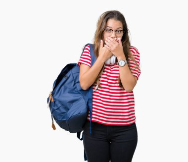 Üzerinde kulaklık ve sırt çantası giyen genç güzel esmer öğrenci kadın arka plan ağız hata için elleriyle kapsayan şok izole. Gizli kavramı.