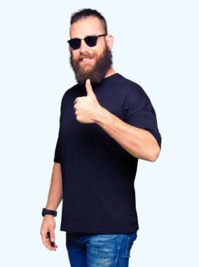Genç hippi erkek hareketi el ile mutlu yaşasın yaparken güneş gözlüğü takıyor. Kameraya bakarak başarı gösteren ile ifade onaylama.