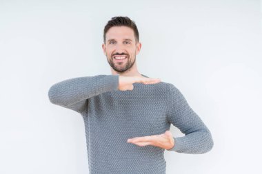 Genç yakışıklı adam, büyük ve büyük boyutlu işareti gösteren eller ile izole arka plan üzerinde Casual kazak giyiyor, ölçmek sembolü. Kameraya bakarak gülümsüyor. Ölçme konsepti.