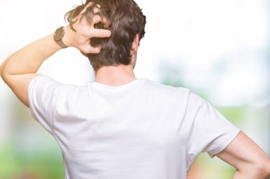İzole arka plan geriye düşünme hakkında şüphe kafasına el ile üzerinden Casual beyaz t-shirt giyen genç yakışıklı adam