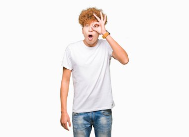 Sürpriz yüz, göz parmaklarının arasından seyir ile ok jest yapıyor casual beyaz t-shirt giyen afro saçlı Genç yakışıklı adam şok. İmansız ifade.