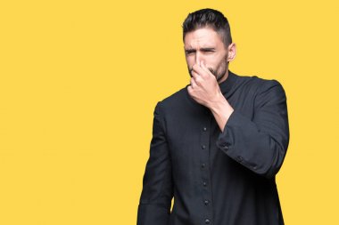 Genç Hıristiyan rahip bir şey pis ve iğrenç kokulu izole arka plan, dayanılmaz koku, holding nefes burun parmaklar ile. Kötü kokuyor kavramı.
