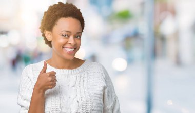 Hareketi el ile mutlu yaşasın yapıyor izole arka plan üzerinde kazak giyen güzel genç Afro-Amerikan kadın. Başarı gösteren kameraya bakarak ifade onaylama.